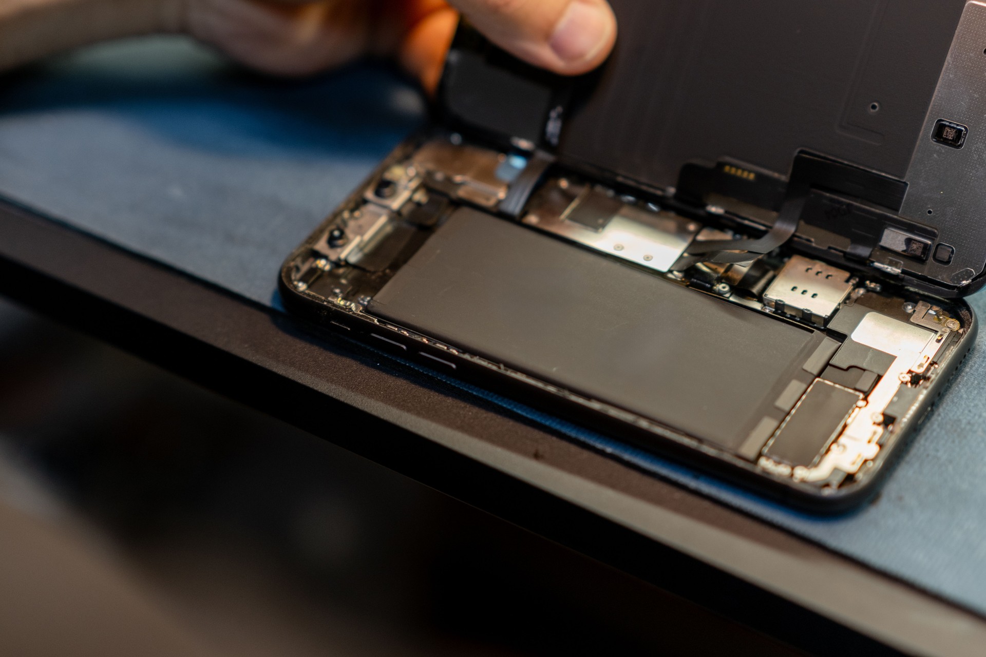Phone Repair Technician Replacing Battery in Smartphone at a Workshop During the Day